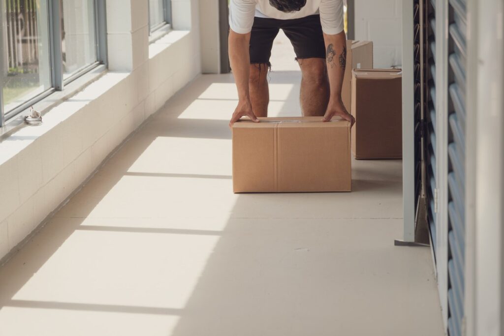 A man loading and unloading moving boxes into his storage unit. 